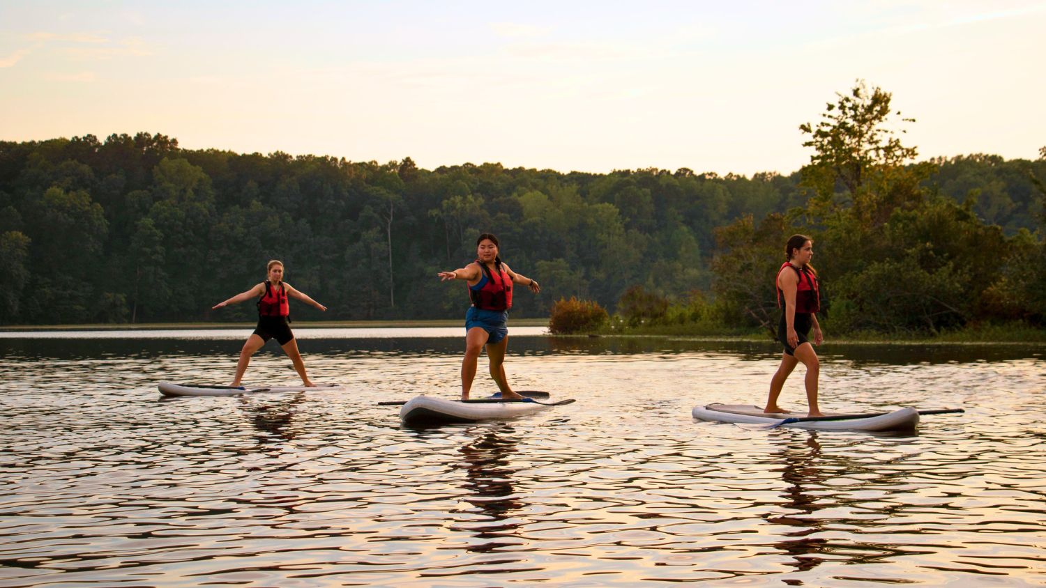 students doing stand up paddleboard yoga on Lake Raleigh