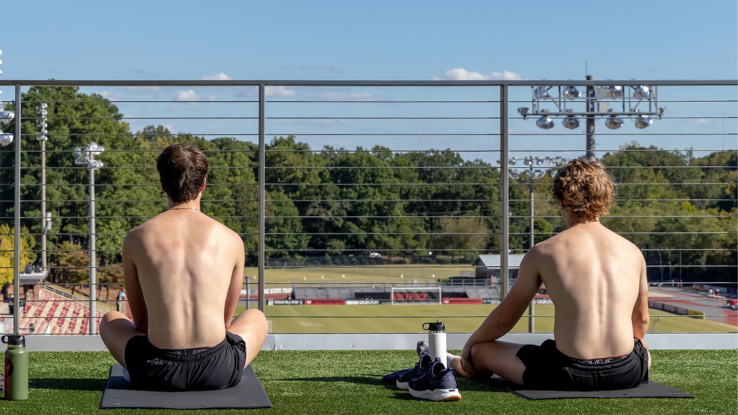 two students stretching on turf balcony