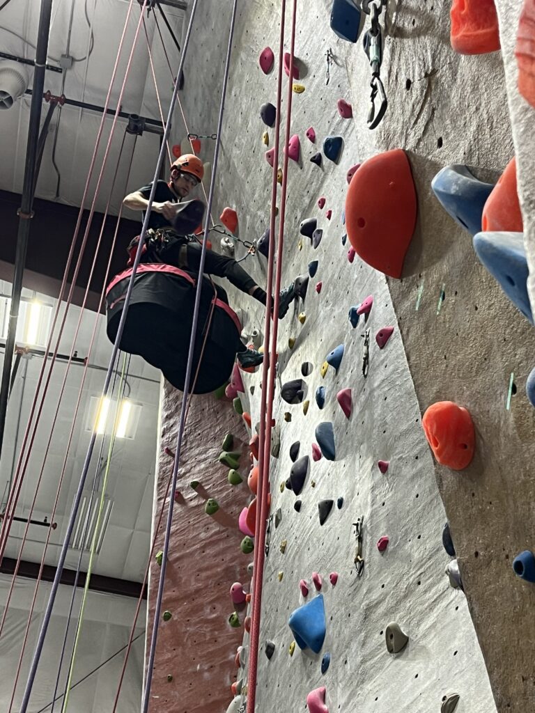 Howard Rhile replacing holds on a climbing wall