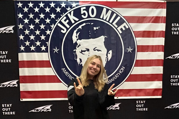 Becca Strong posing in front of the JFK 50 Mile banner